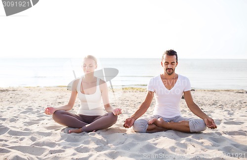 Image of smiling couple making yoga exercises outdoors