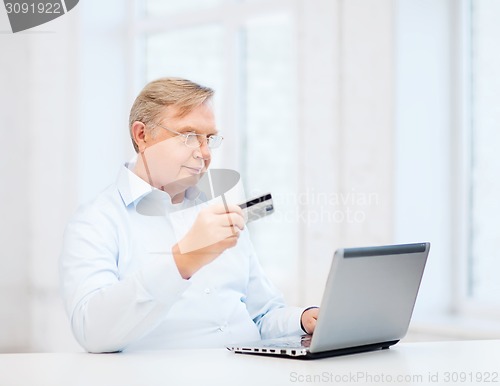 Image of old man with laptop and credit card at home