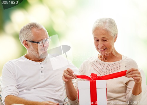 Image of happy senior couple with gift box at home