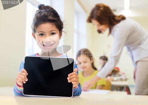 Image of little school girl with tablet pc over classroom