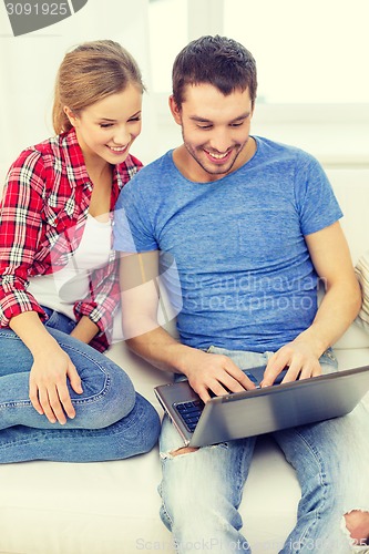 Image of smiling couple with laptop computer at home