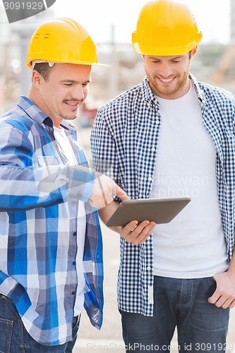 Image of smiling builders with tablet pc outdoors