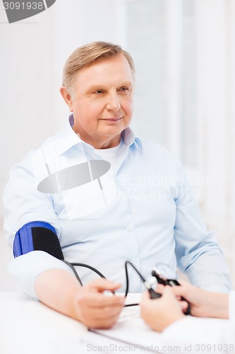 Image of female doctor or nurse measuring blood pressure