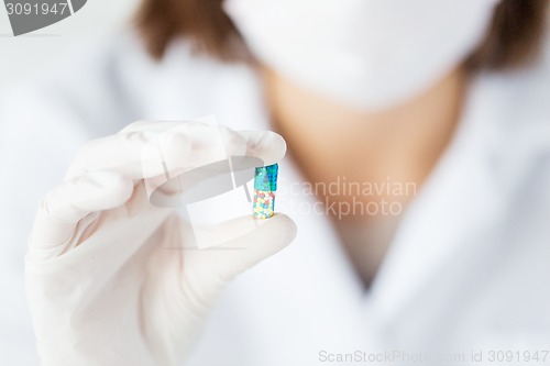 Image of close up of scientist holding pill in lab