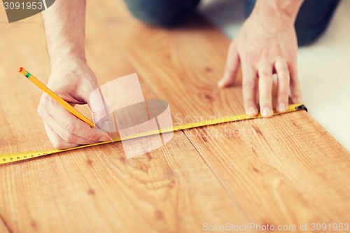 Image of close up of male hands measuring wood flooring