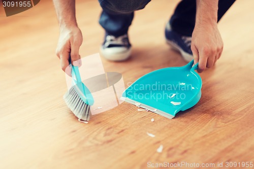 Image of close up of male brooming wooden floor