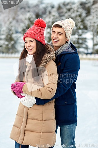 Image of happy couple ice skating on rink outdoors