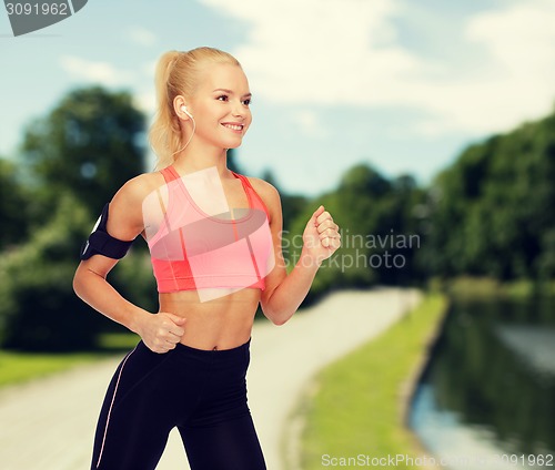 Image of sporty woman running with smartphone and earphones