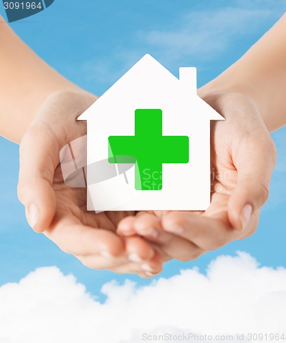 Image of hands holding paper house with green cross