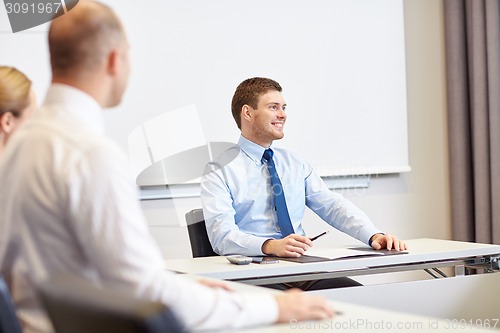 Image of group of smiling businesspeople meeting in office