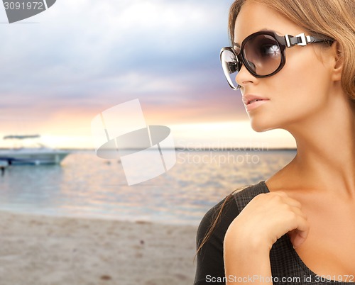 Image of young woman in shades over sea shore background