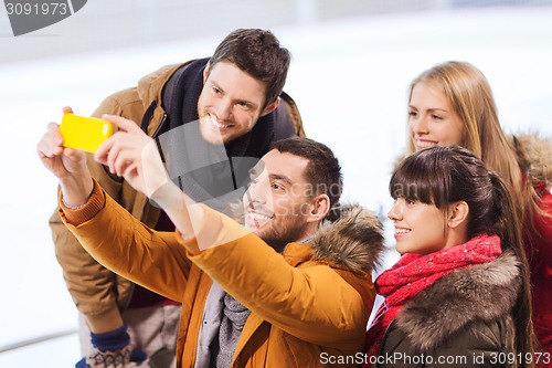 Image of happy friends with smartphone on skating rink