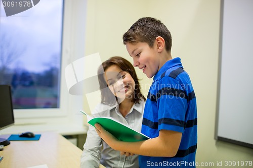 Image of school boy with notebook and teacher in classroom