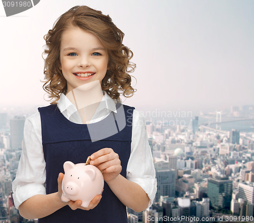 Image of smiling girl putting coin into piggy bank
