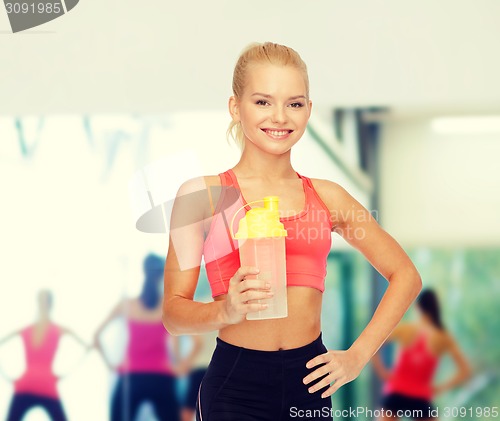 Image of smiling sporty woman with protein shake bottle