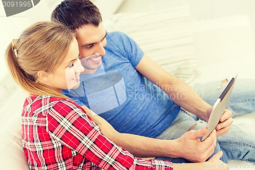 Image of smiling happy couple with tablet pc at home