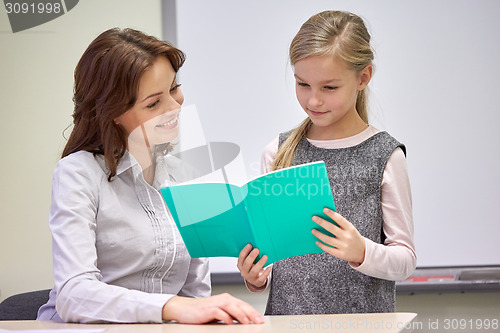 Image of school girl with notebook and teacher in classroom