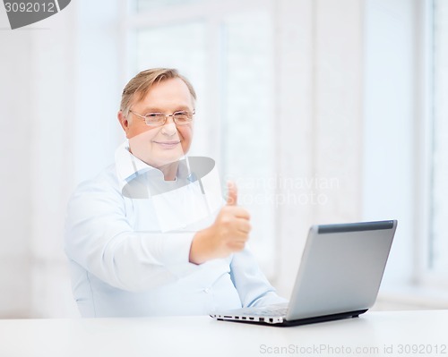 Image of old man with laptop computer showing thumbs up