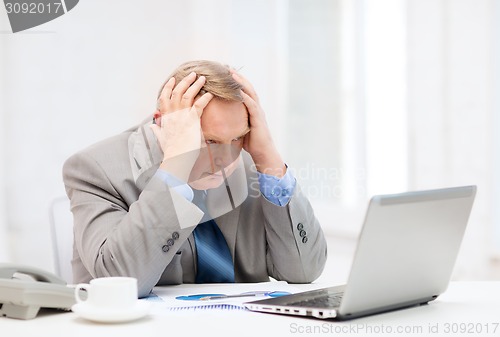 Image of upset older businessman with laptop and telephone