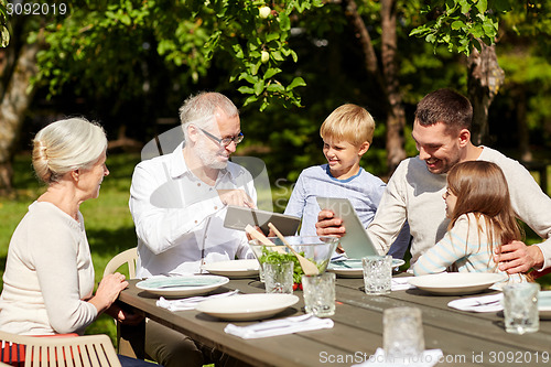 Image of happy family with tablet pc at table in garden