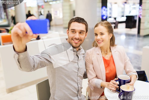 Image of happy couple with smartphone taking selfie in mall