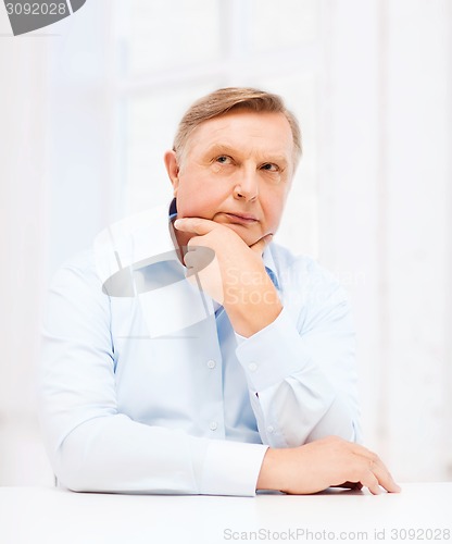 Image of stressed old man holding head at home