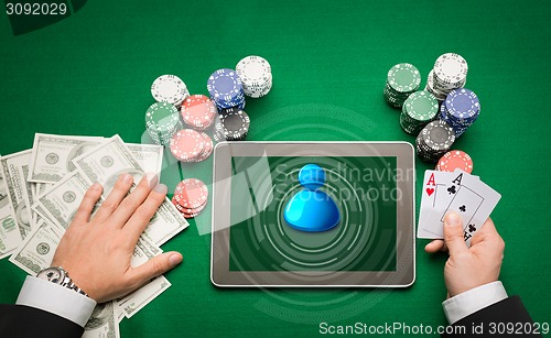 Image of casino poker player with cards, tablet and chips