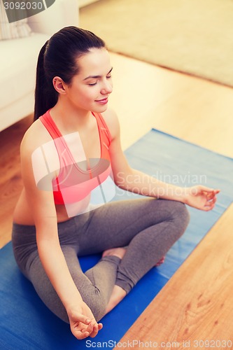 Image of smiling teenager meditating at home