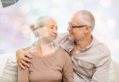 Image of happy senior couple hugging on sofa at home