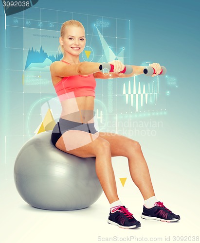 Image of woman with dumbbells sitting on fitness ball