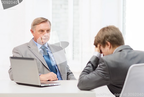 Image of older man and young man having argument in office