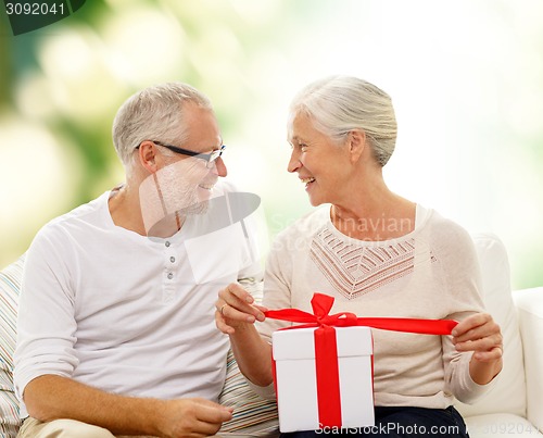 Image of happy senior couple with gift box at home