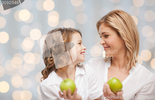 Image of happy mother and daughter with green apples