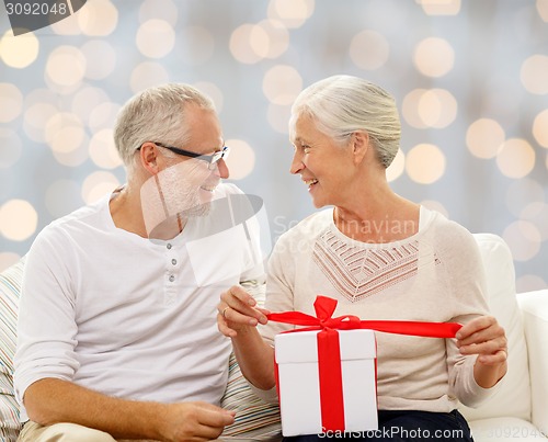 Image of happy senior couple with gift box at home