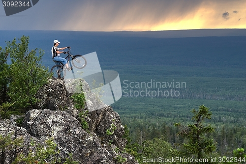 Image of Biker with mountain bicycle stands on peak