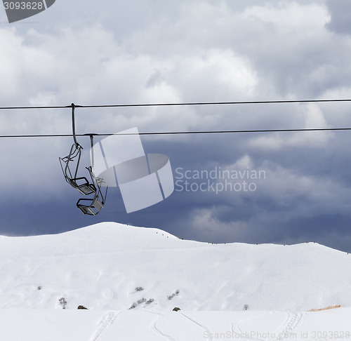 Image of Chair lifts and off-piste slope at windy gray day