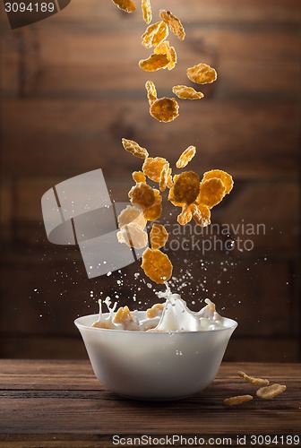 Image of Falling corn flakes with milk splash on wood