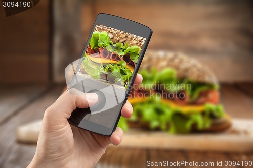Image of Hand taking photo of sandwich with smatphone 