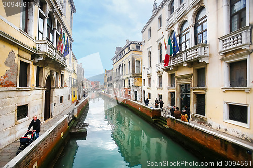 Image of People walking in sidewalks of water canal