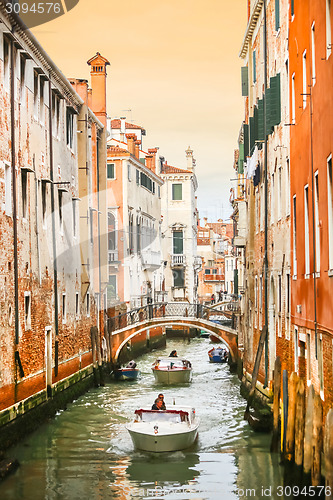 Image of Boats sailing in water canal with orange buildings