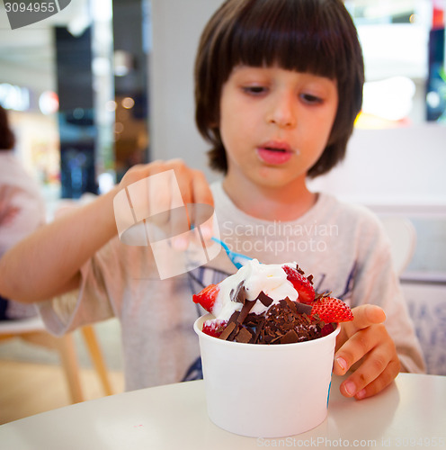 Image of boy eating ice cream with chocolate and strawberries