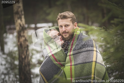 Image of Young couple winter forest walk in a warm blanket 