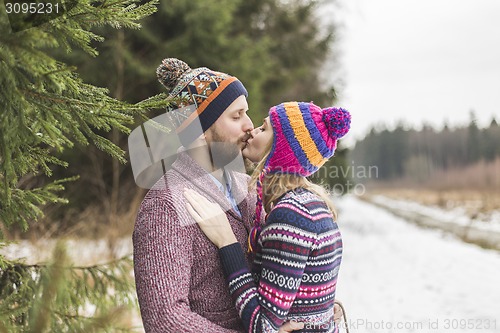 Image of Young peaople are kissing in winter forest