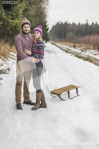 Image of Young couple having a sled winter forest walk