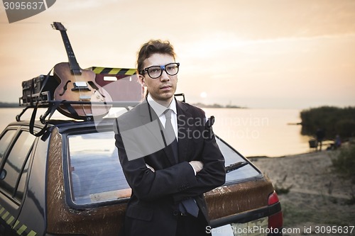 Image of Musician old cheap car and guitar