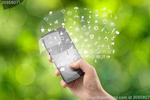 Image of Hand holding smartphone with icons on green background