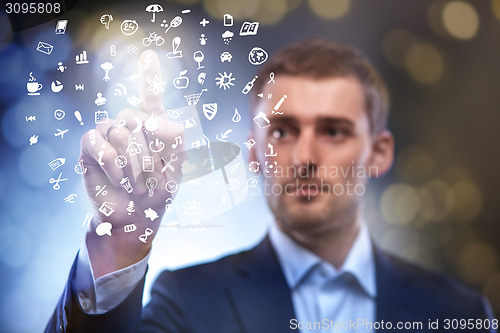 Image of business man pressing button with set of icons in air