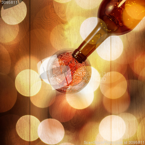 Image of Red wine pouring into glass from bottle on white wooden table. T