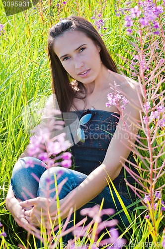 Image of Beautiful brunette female sitting in field