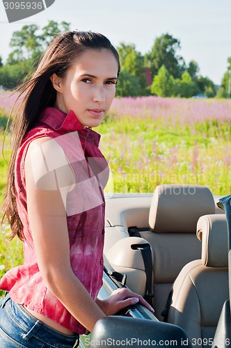 Image of Beautiful brunette female standing near car